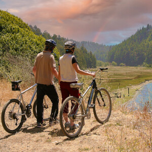 couple overlooking big river holding hands and their bicycles